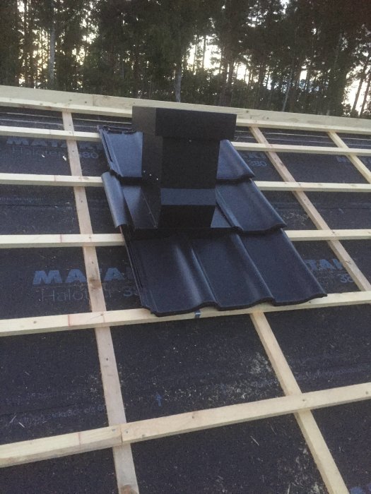 Huv för köksfläkt och värmepump installerad på tak med svart plåt Magestic från Lindab.