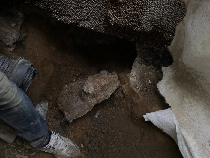 Utsikt över en nygrävd pumpgrop vid källargrund, med synlig dräneringsisolering och berggrund.