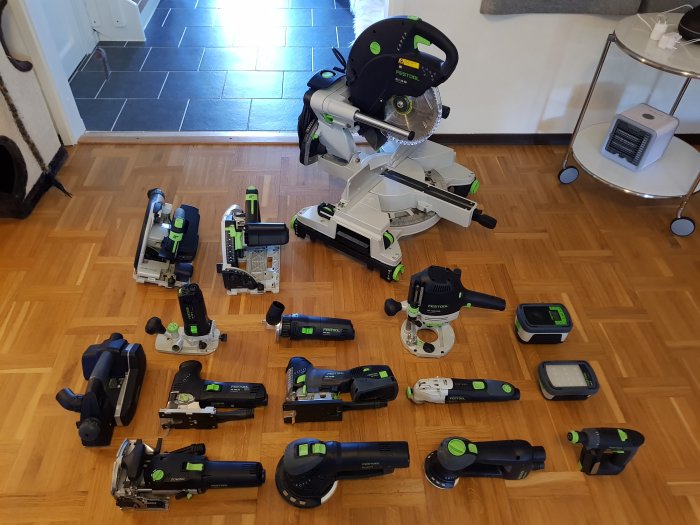 En samling verktyg från Festool utspridda på ett trägolv i ett hem.