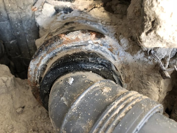 Närbild på en rostig och dammig röranslutning under renoveringsarbetet.