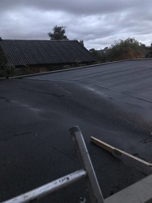 Tak med pappbeklädnad och synlig vallning samt tumstock som markerar läckområde.