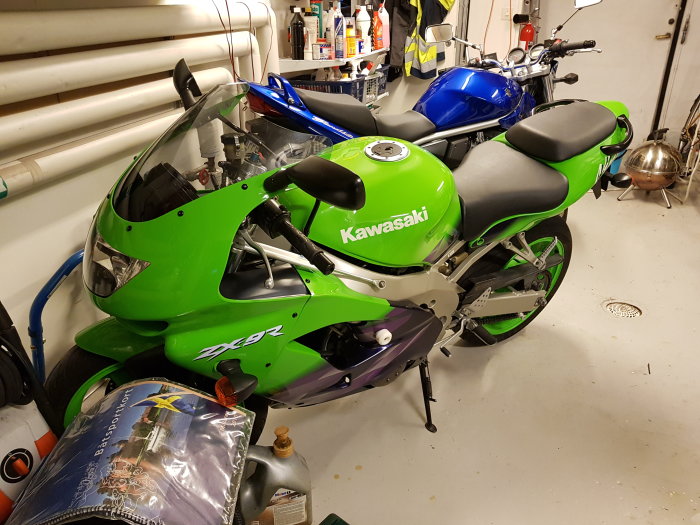 Grön och lila Kawasaki ZX-9R motorcykel från 1999 i ett garage med verktyg och renhållningsprodukter.