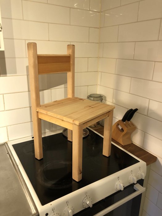 Handgjord trästol placerad på ett köksspis, nyoljad och redo för bedömning.