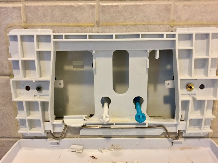 Öppen inbyggd WC-cistern utan frontpanel som visar interna mekanismer och rörkopplingar.