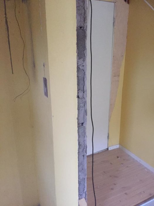 En öppning i en källarvägg med lekablock och gula väggar, redo för renovering.