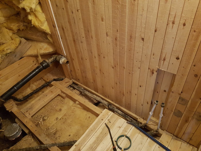 Renoveringsarbete på toalett med exponerade rör och avloppsstam i schakt.