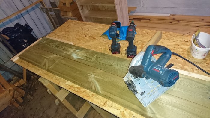 Bosch GKS 55 G cirkelsåg och andra verktyg på ett träarbetsbord i ett byggprojekt.