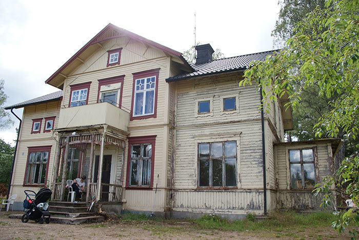 Sekelskifteshus under renovering med familj på farstukvisten och barnvagn framför.