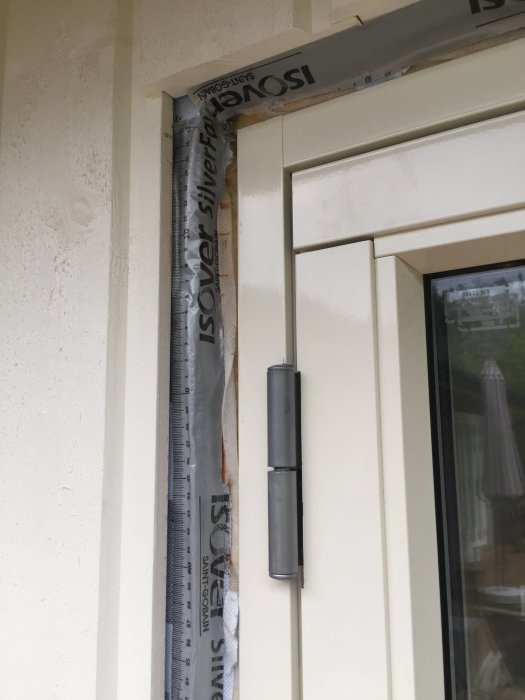 Närbild på sidan av en altandörr och dess karm med vindskydd och aluminiumdetaljer.