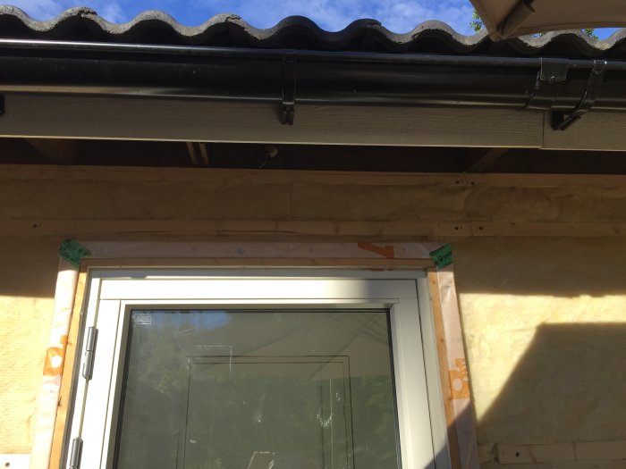 Nyinstallerat fönster med tilläggsisolering och vindskydd under pågående arbete.
