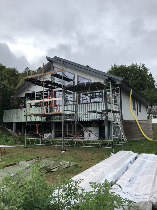 Ett tvåvåningshus under renovering med ställningar och byggmaterial runtomkring.