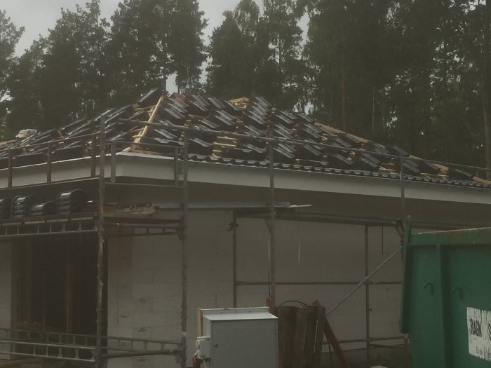 Takstolar med upplagda men ej färdiglagda takpannor av modellen Tiefa Supra på ett hus under konstruktion.