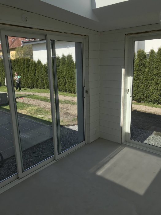 Nyinstallerade fönster och skjutdörrar i ett bygge med utsikt mot en gräsmatta.