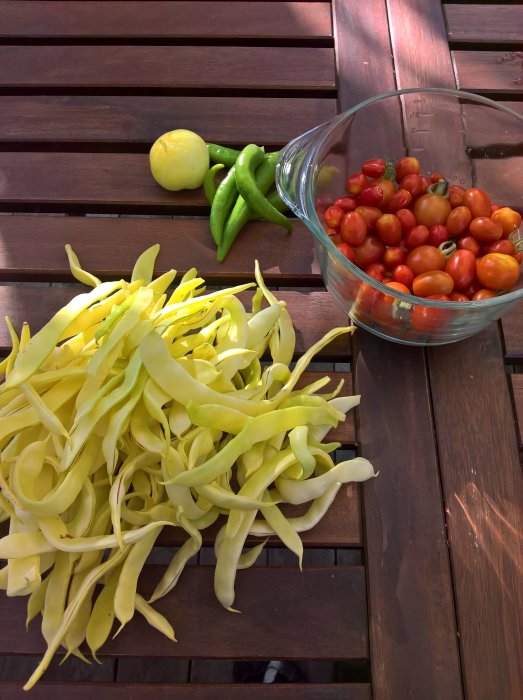Skörd av tomater, squash och paprika på träbord, skuggspel från solen.