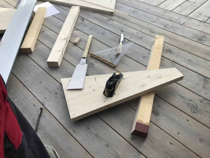 Trädelar och verktyg för att bygga spiraltrappa spridda på en träterrass.