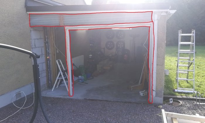 Garage med nästan helt riven vägg och röd markering där väggen ska byggas. Takregel synlig i toppen.