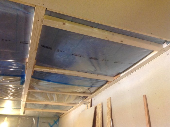 Installation av OSB-skivor i taket med synliga reglar och isolering i en verkstad under renovering.