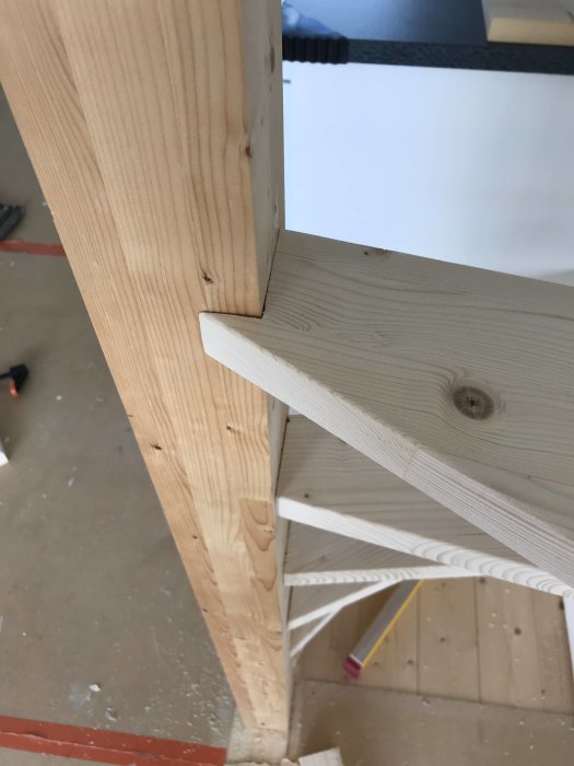 Delvis färdigbyggt trätrappsteg med synlig konstruktionsdetalj, i ett pågående byggprojekt.