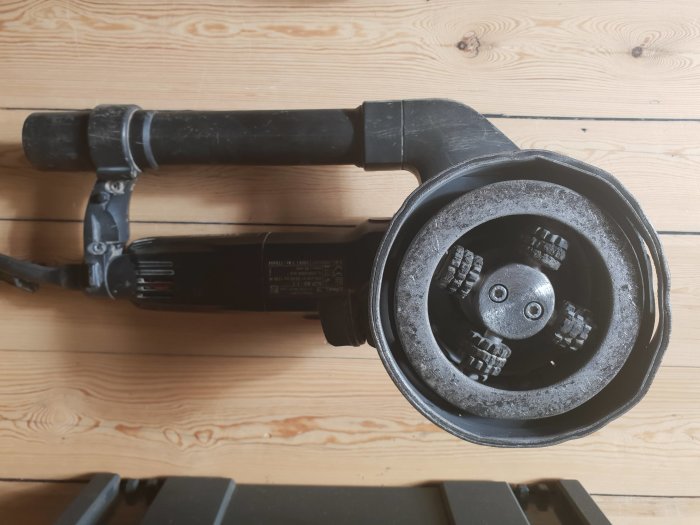 Använd Protool saneringsfräs placerad på trägolv, dammkåpan uppvisar slitage och sprickor.