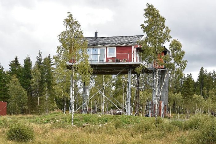 Rött hus på pålar omgivet av skog i Östra kvarnskogen, Sollentuna, exempel på miljövänligt stylthus.