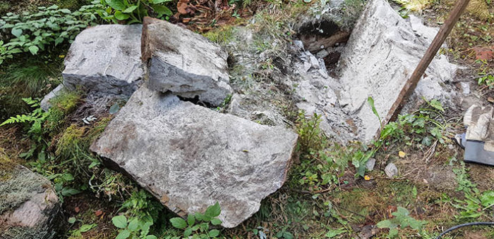 Stora stenhuggararbeten med verktyg i en trädgård, stenblock delade i flera bitar.
