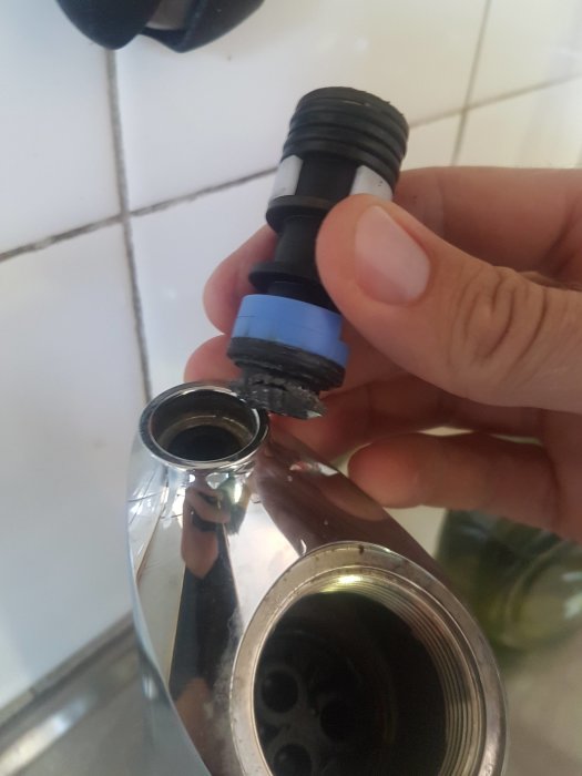 Avbruten plastdel mellan köksblandarens pip och kropp visas i någons hand.