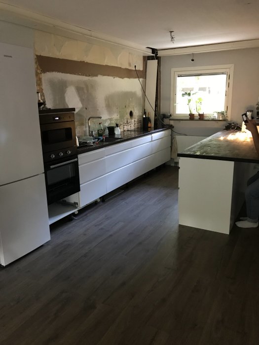 Ett kök under renovering med oputsade väggar och hål för utluft ovanför spisen.