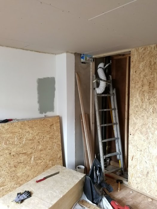 Renoveringsarbete i sovrum med nya väggar i gips och OSB, samt arbetsmaterial och verktyg synliga.