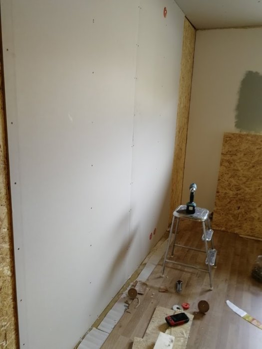 Renovering av sovrum med ny gipsvägg och OSB-skivor, verktyg och byggmaterial på golvet.
