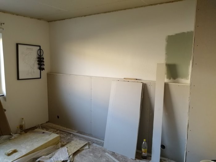 Delvis renoverat sovrum med nybyggd vägg och oslipade gipsskivor, isoleringsmaterial och konstruktionsmaterial synliga.