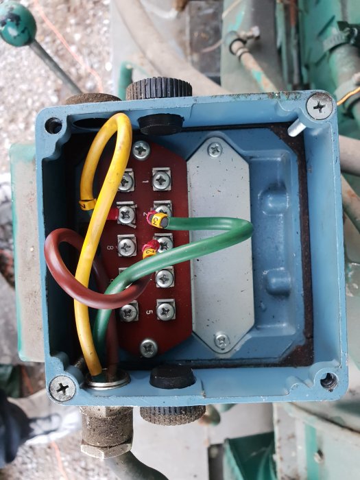 Närbild av insidan av en varvtalsregulator med hoprullad kabel och anslutna kablar i en öppen kapsling.