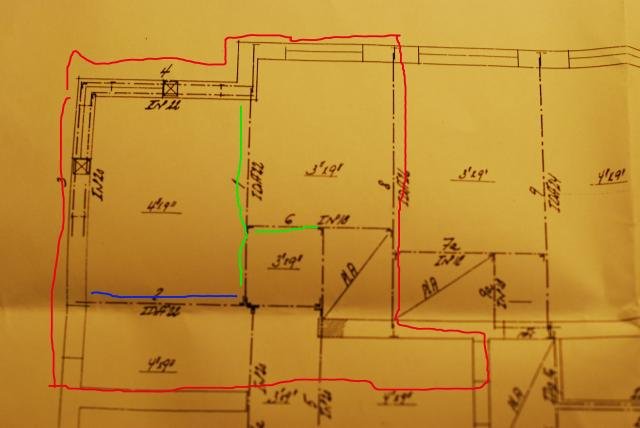 Blueprint of an apartment with red outline, green-marked walls considered for removal, and a previously removed wall marked in blue.