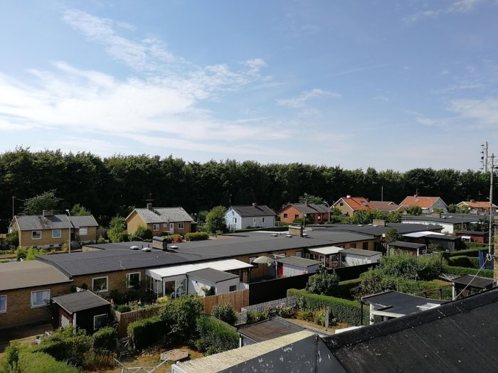 Utsikt över ett bostadsområde med enfamiljshus från en högre punkt under klar himmel.