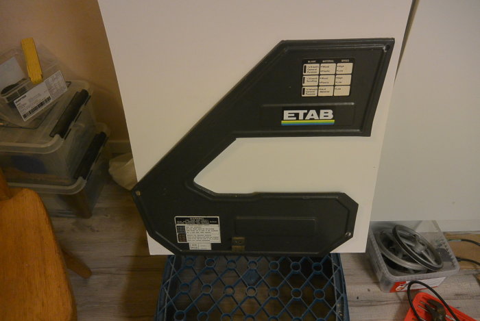 Svart bänk bandsågsdel märkt med "ETAB", med instruktionsdekal, placerad inne i ett arbetsrum.