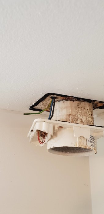 Gammal badrumsfläkt med mögel och synliga kablar i taket.
