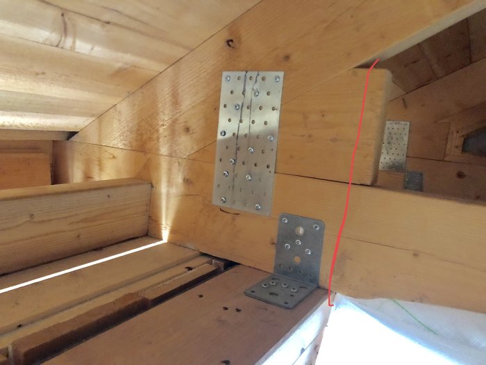 Trätimmerkonstruktion med metallbeslag och överarm markerad i rött för byggprojekt.