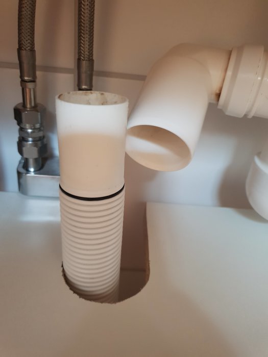 Vattenläckage vid felaktigt anslutna rör under handfatet, med synlig avloppsrörskoppling.