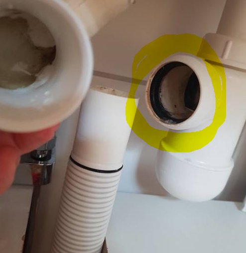 Hand håller ett avlägsnat vattenlåsrör nära ett öppet Prevex Preloc vattenlås, möjlig fråga om rörets diameter.