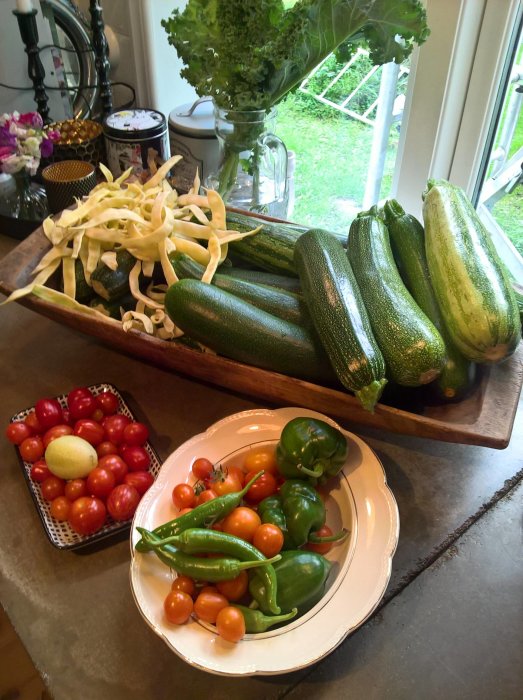 Skörd av zucchini, tomater, paprika och ärtskidor på köksbänk.