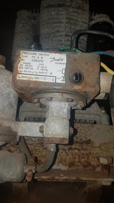 Grovgängad tryckbrytare för kompressor med etikett från Danfoss, monterad på metallrör.