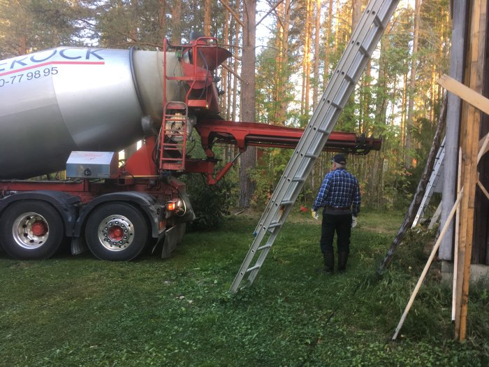 Person som tittar på en betongbil som transporterar betong via en ränna till en byggarbetsplats.