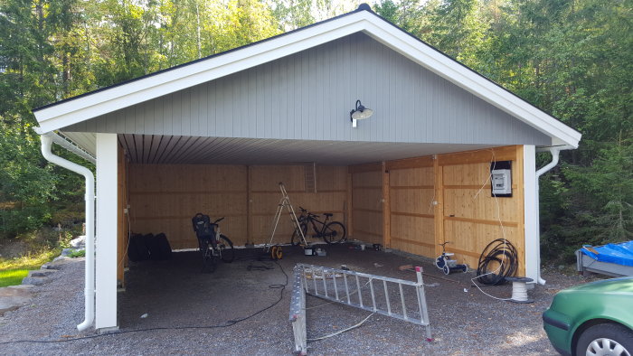 Nymålat carport med uppsatta lampor och eluttag, väntar på elinstallation.