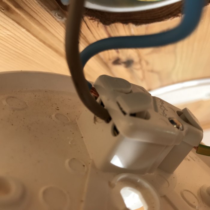 Närbild på ett öppet eluttag under installation med synliga kablar.