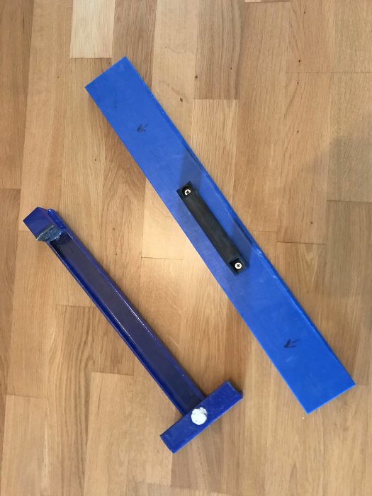 En blå baksmälla i metall och en blå slagkloss i plast på ett trägolv, till försäljning.