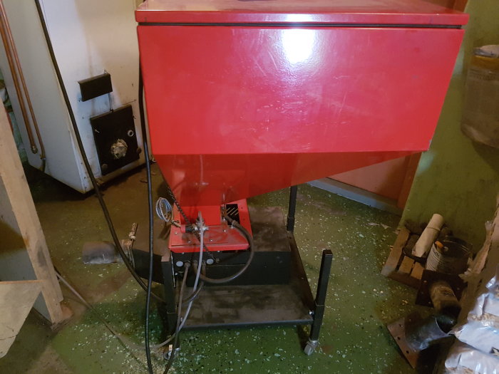 Pelletsbrännare Pelda 21 i ett pannrum med synlig motor och växellåda, omgiven av verktyg och byggmaterial.