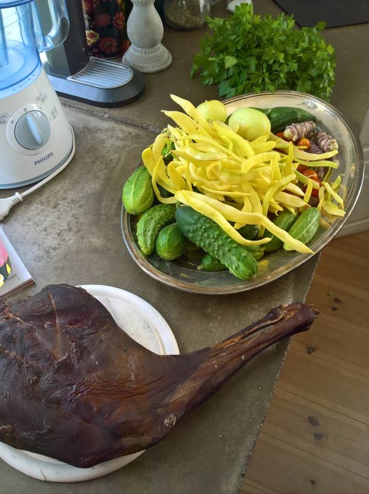 En skål med jordärtskockor och squash vid sidan av en stor köttbit på ett bord.