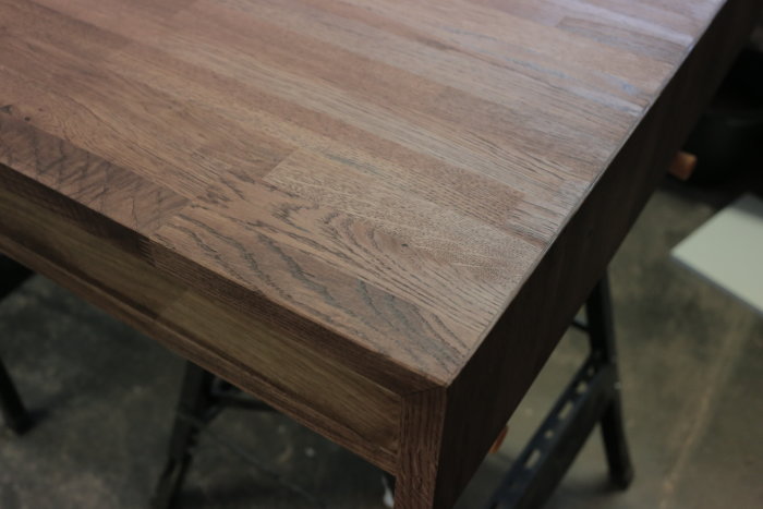 Träskrivbord med synlig limfog och sågspån för att dölja en glipa.