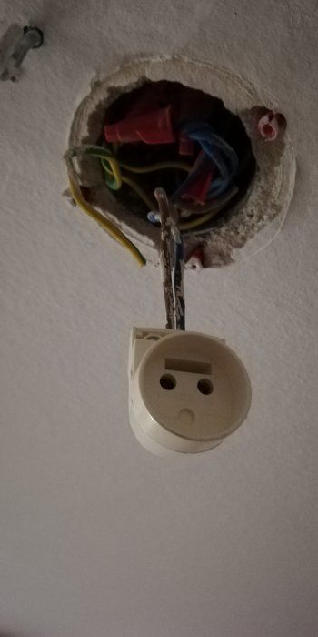 Installation av eluttag med oskyddade kablar och anslutningar i öppet hål i väggen.