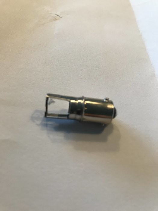 Glödlampa med bajonettfattning på vit bakgrund med avsläppt glödtråd, tillhör Kero 260.