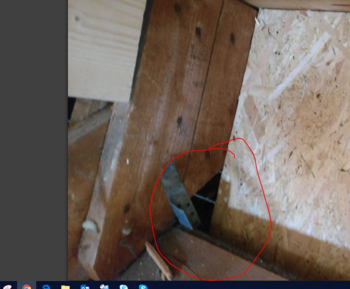 Hörnet av ett bygge med OSB-skiva intill gammalt trägolv och råspont, markerad glipa synlig.